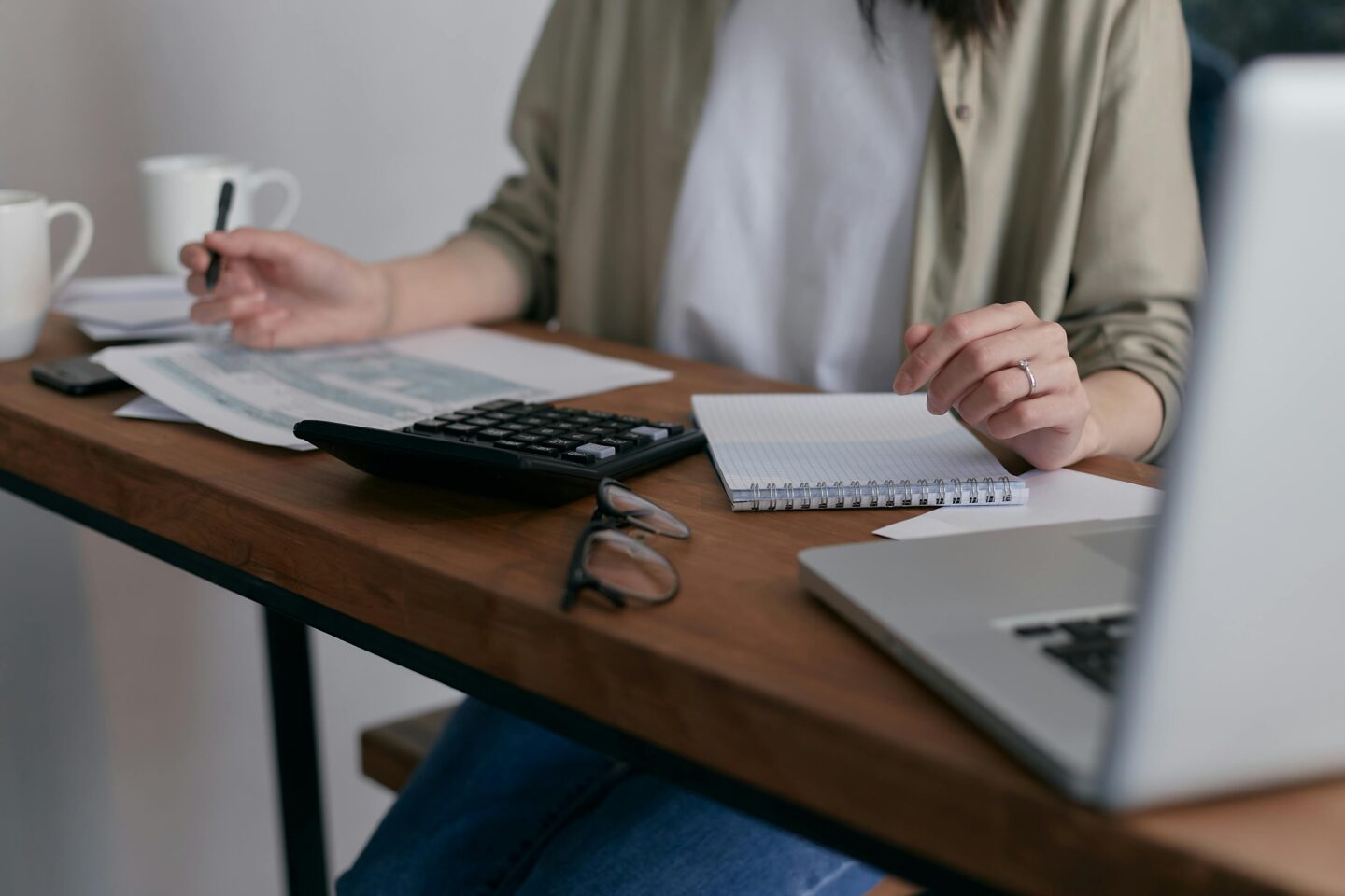 A clean, minimalist workspace with a single laptop and a plant, demonstrating how an organized environment enhances focus.